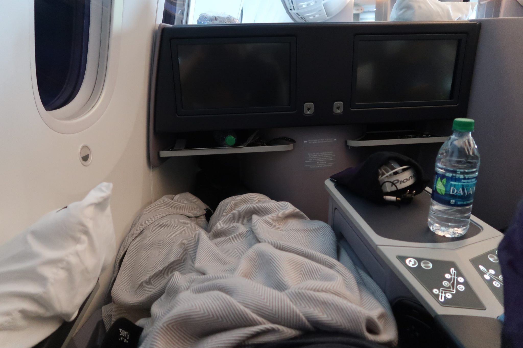 a bed with a blanket and a tv on the side of a plane