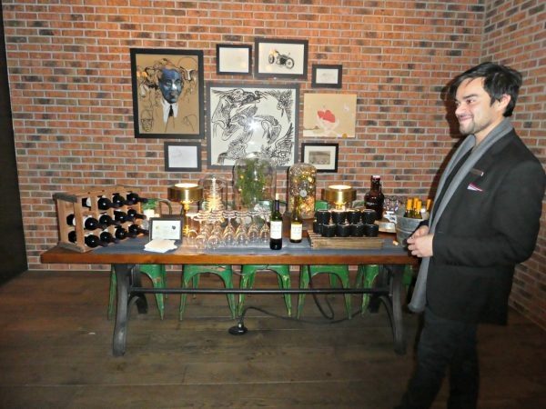 a man standing next to a table with bottles of wine
