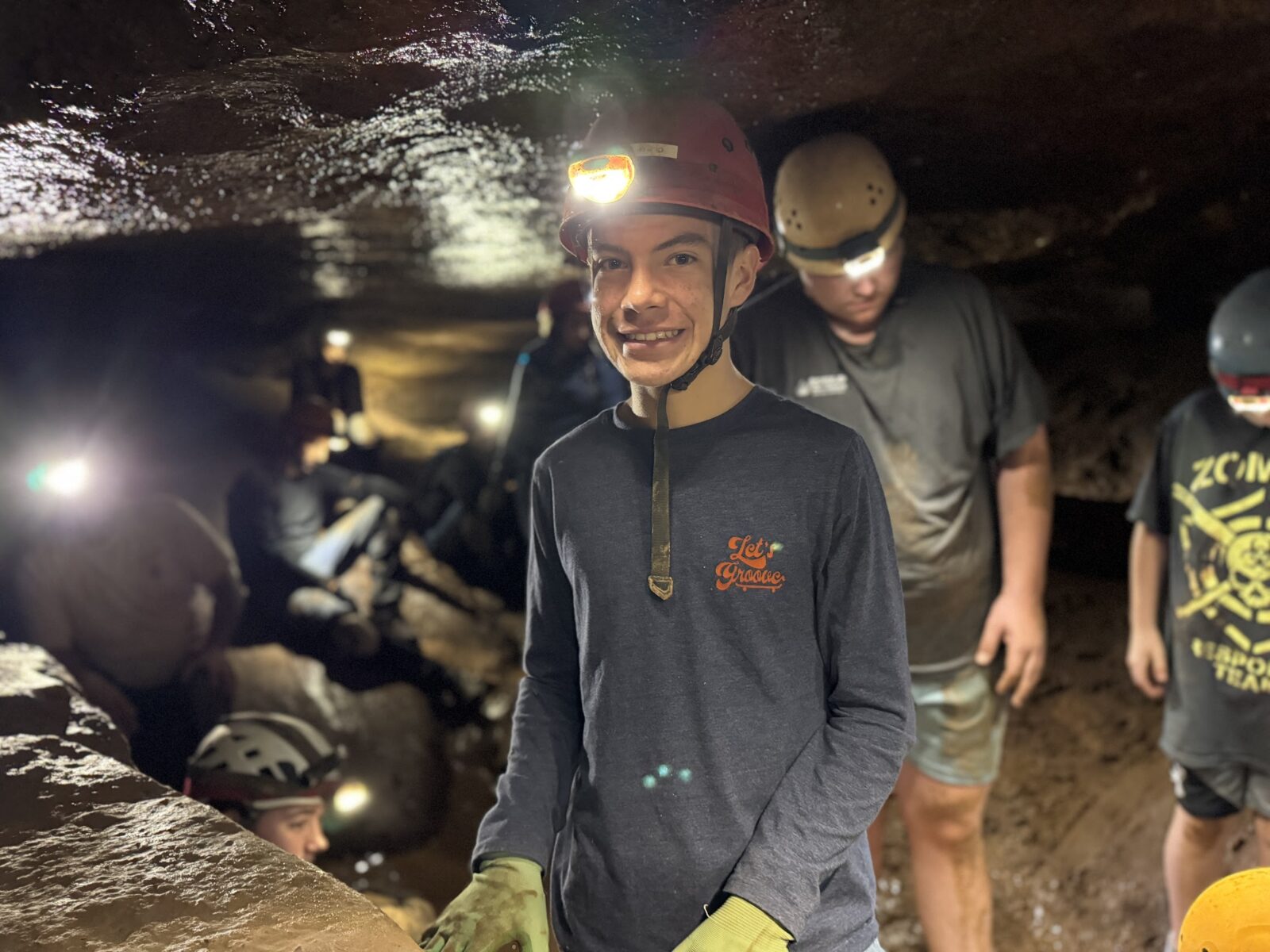 a boy wearing a helmet and standing in a cave